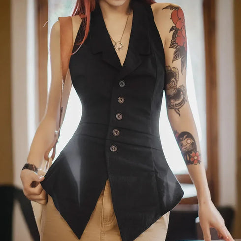 Person wearing a black sleeveless blazer with tattoos on arms, indoors.